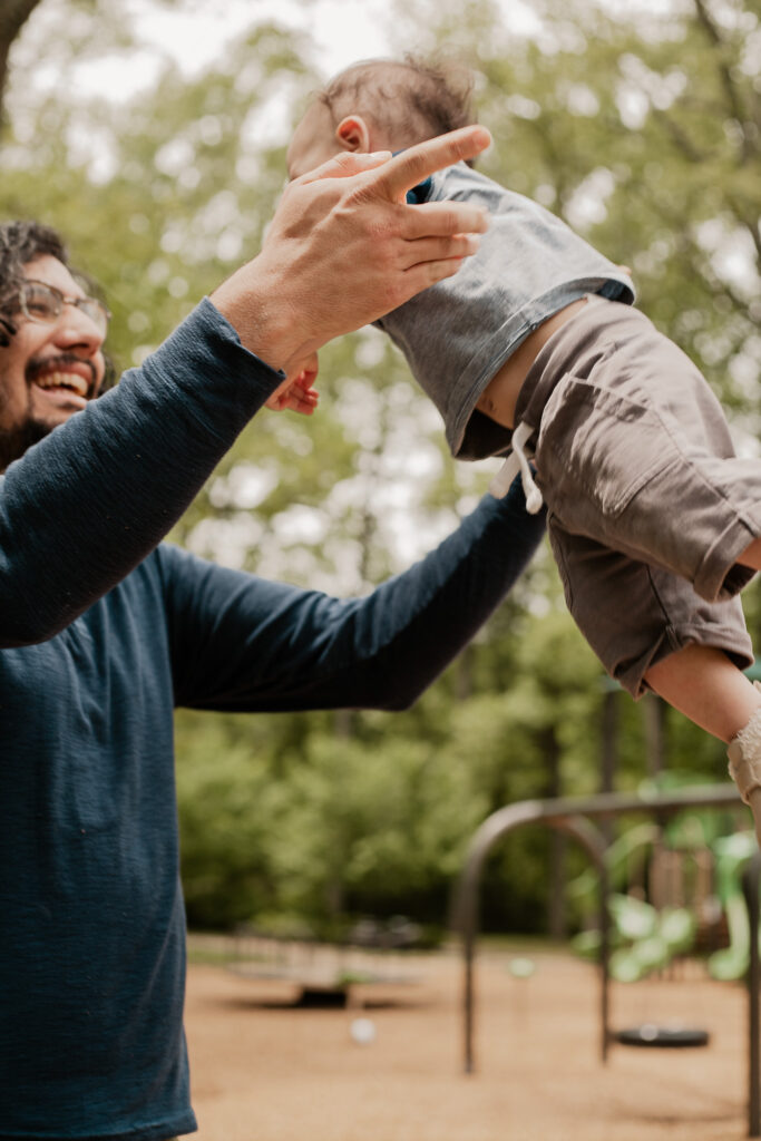 Family photo session in Atlanta, GA with dad swinging baby in playground