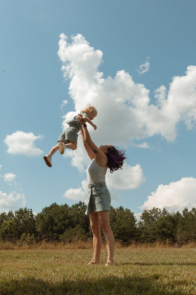Mom throwing toddler up in the air while playing during family session with toddler in Atlanta, GA